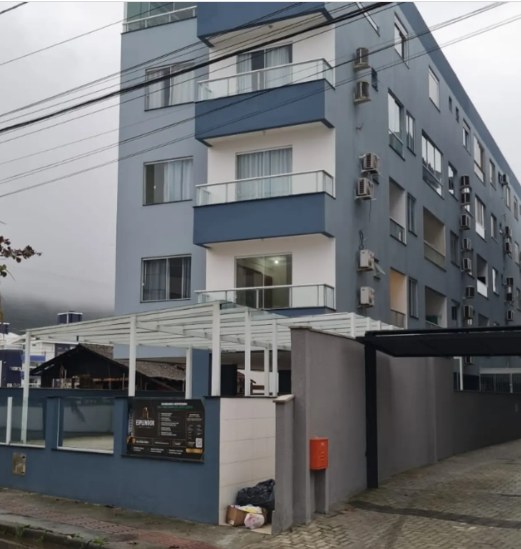 Lateral do Condomínio Residencial Davi Miguel com sacadas e muro azul após a pintura