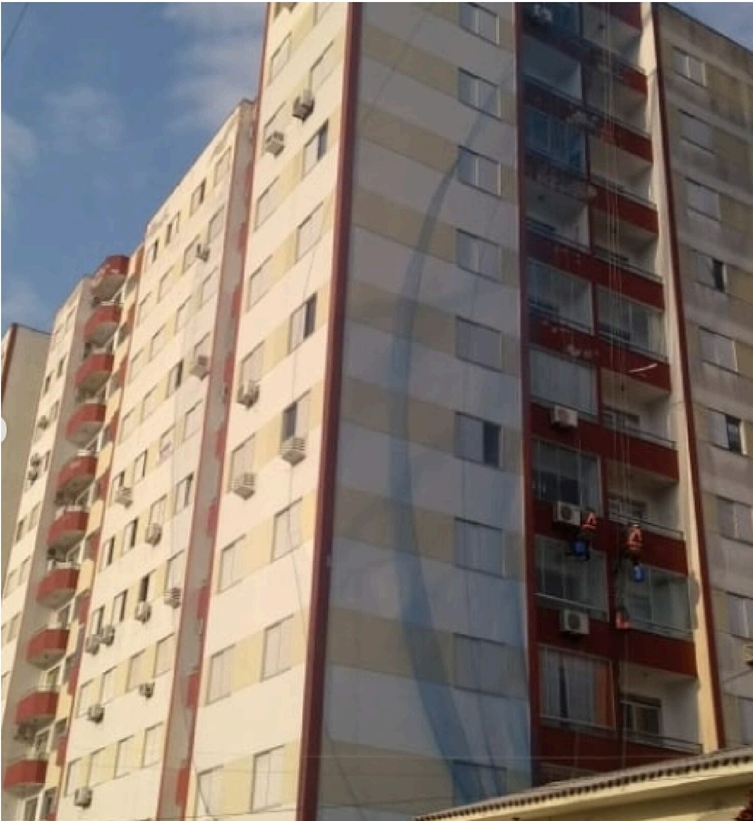 Equipe trabalhando em cordas na fachada de edifício residencial